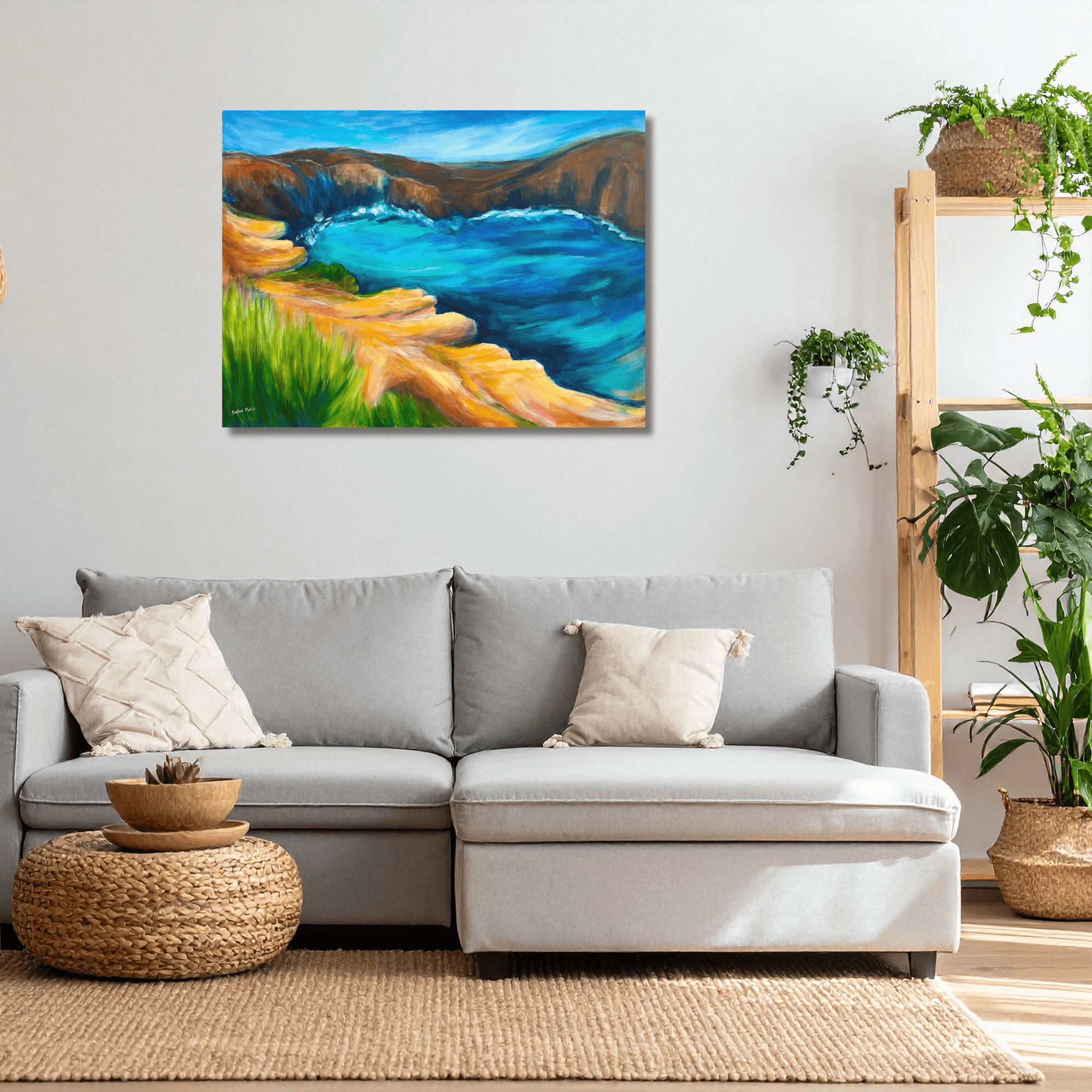Living room with a gray sofa, woven ottoman, and a colourful Wester Australian landscape painting on the wall.